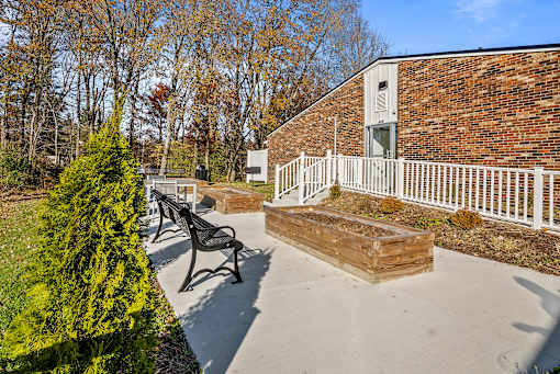 A brick building with a white fence and a bench in front.