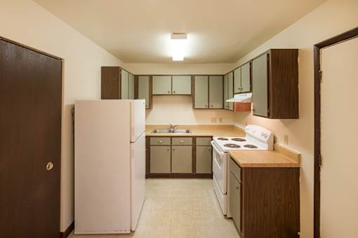 A kitchen with a white refrigerator and brown cabinets.