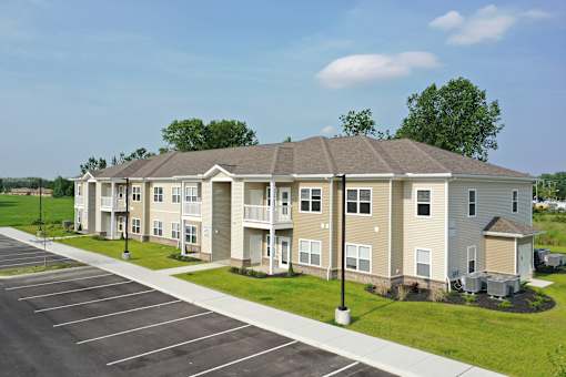 Apartment complex with a parking lot in front.
