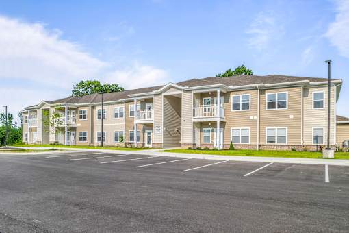 A large apartment complex with a parking lot in front.
