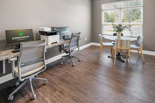 A room with a desk, chairs, and a laptop with the logo "SUMMERGROVE" on it.