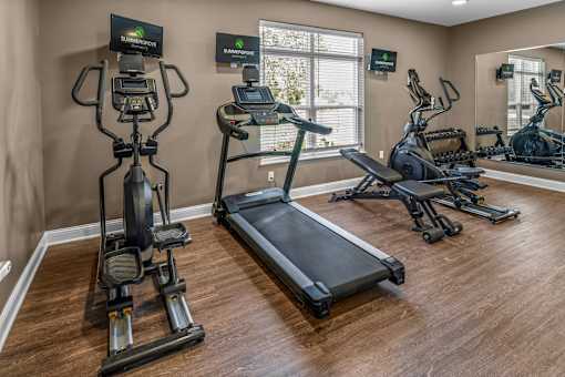 A home gym with a treadmill, elliptical trainer, and stationary bike.