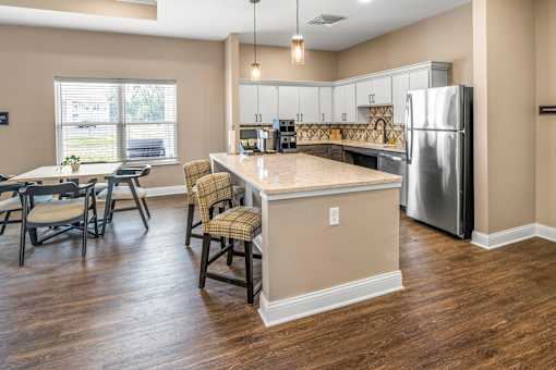 A kitchen with a table and chairs in front of a refrigerator.