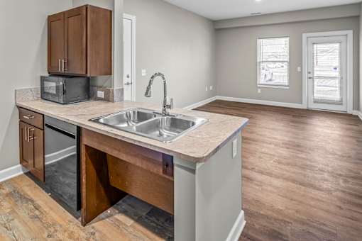 A kitchen with a sink and a microwave on the counter.