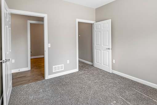 A room with two white doors and a carpeted floor.