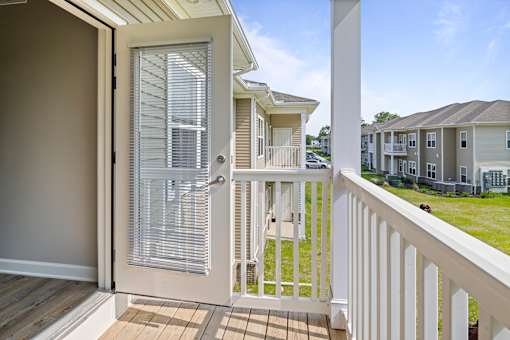 A balcony with a white railing and a sliding door leading to a patio.
