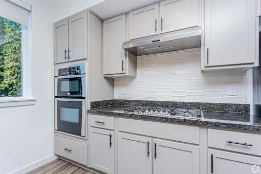 A kitchen with white cabinets and a granite countertop.