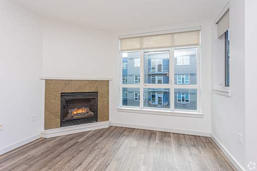 A room with a fireplace and a window showing a building outside.