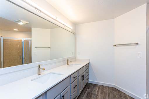 A bathroom with a white counter top and a large mirror.