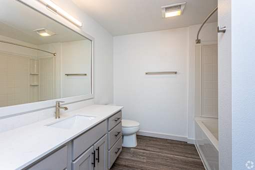 A white bathroom with a toilet, sink, and mirror.