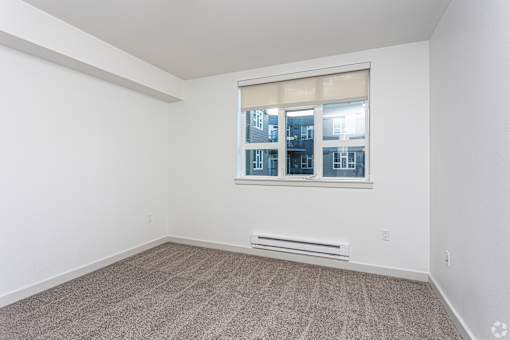 A room with a window and a bench under it.
