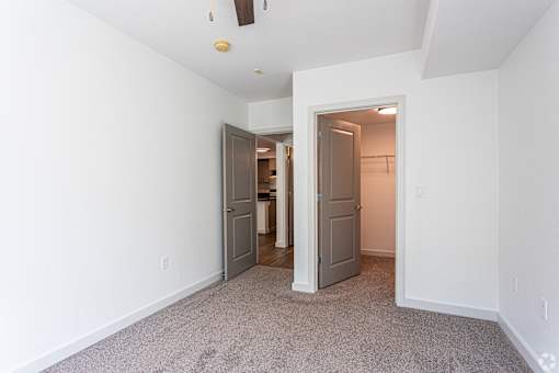 A room with a carpeted floor and two doors.