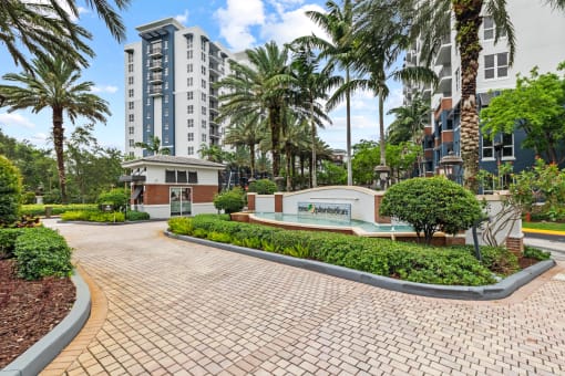 a pathway leading to a building with palm trees and a fountain