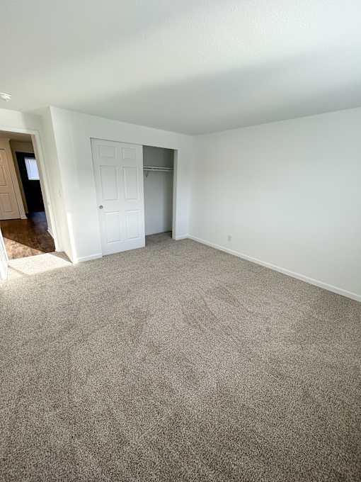 A room with a carpeted floor and a white door at 2000 Lake Washington Apartments, Renton, WA
