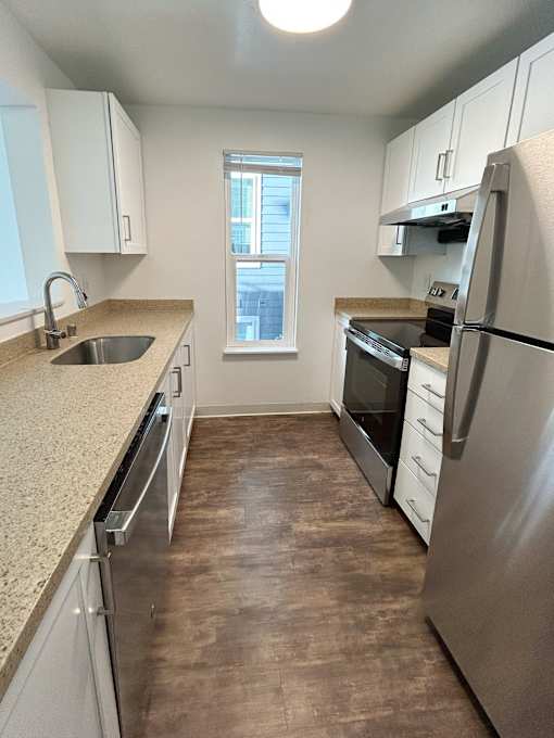 A kitchen with a stainless steel refrigerator, sink, and wooden flooring at 2000 Lake Washington Apartments, Renton, WA, 98056