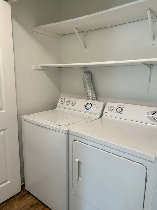 A white washing machine and dryer in a small laundry room at 2000 Lake Washington Apartments, Renton, 98056