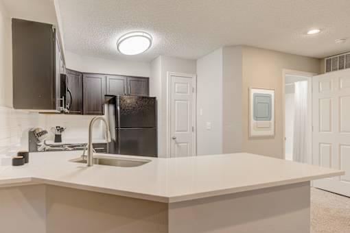 A kitchen with a sink and a refrigerator at Ashford Belmar in Lakewood, CO 80226