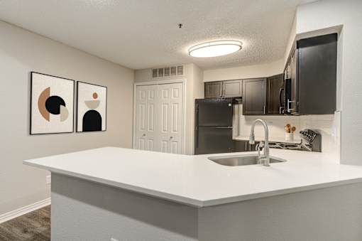 A kitchen with a white countertop and a black refrigerator at Ashford Belmar in Lakewood, Colorado 80226