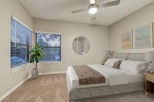 A bedroom with a large bed, a potted plant, and a ceiling fan at Ashford Belmar in Lakewood, CO 80226