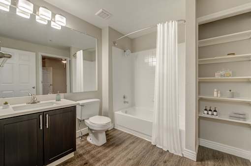 A white bathroom with a toilet, sink, and bathtub at Ashford Belmar in Lakewood, CO 