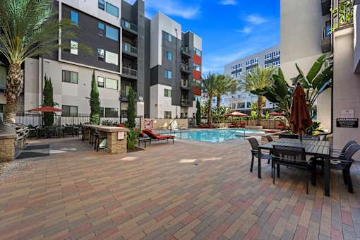 A patio with a table and chairs overlooking a pool.