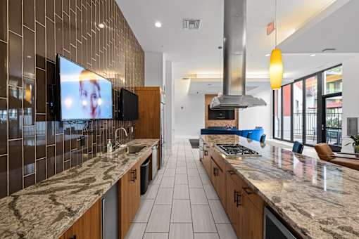 A modern kitchen with a marble countertop and a television mounted on the wall.