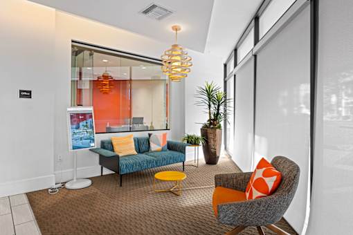 A modern living room with a grey sofa, a yellow chair and a glass wall.