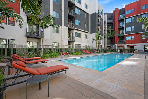 A pool surrounded by a patio with chairs and a table.