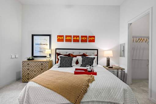 A bedroom with a large bed and a dresser with a mirror.