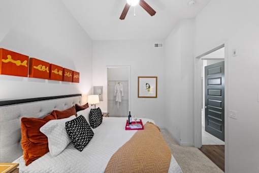 A bedroom with a bed, pillows, and a ceiling fan.