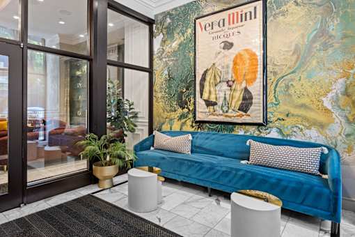 A blue sofa with a pillow and a magazine on the wall.