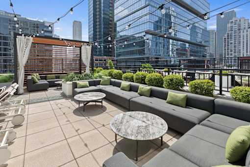 A patio with a couch, table and chairs with a cityscape in the background.