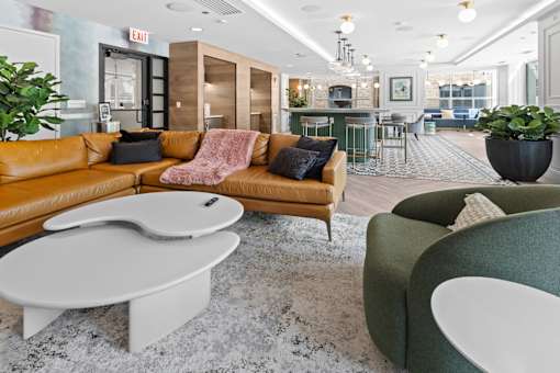 A modern living room with a brown sofa, a green armchair, and a white coffee table.