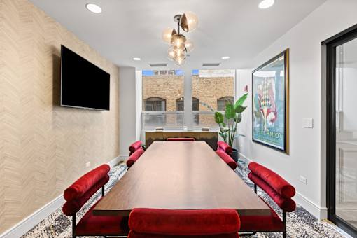 A conference room with a long table and red chairs.