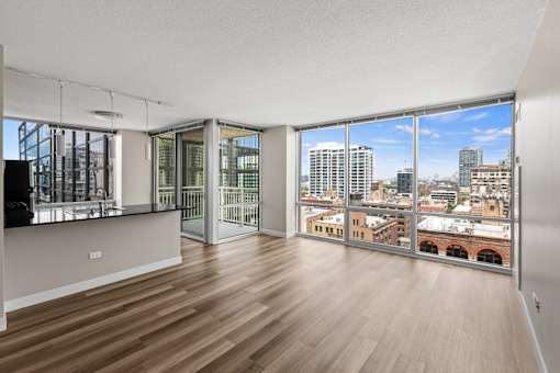 A room with wooden floors and a view of the city through large windows.