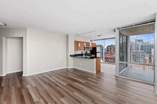 A room with wooden floors and a kitchen area with a view of the city.