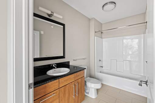 A bathroom with a sink, mirror, toilet, and bathtub.