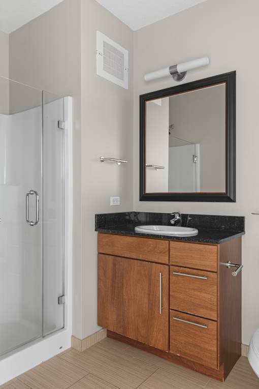 A bathroom with a sink, mirror, and shower.