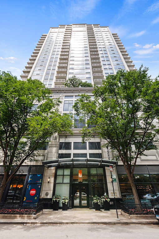 A tall building with a curved entrance and trees in front.