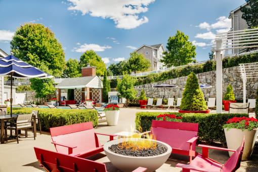 a patio with red chairs and tables and a fire pit at Residences at Stevens Pond, Massachusetts, 01906