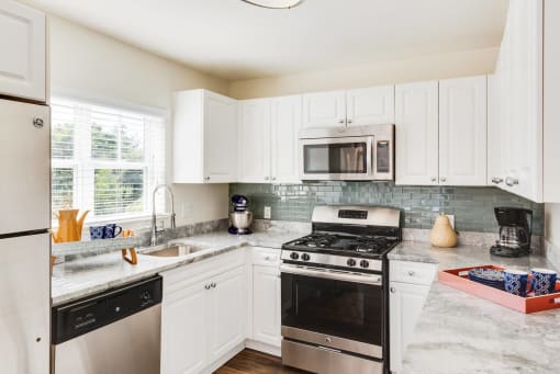 a kitchen with stainless steel appliances and white cabinets at Residences at Stevens Pond, Saugus, 01906