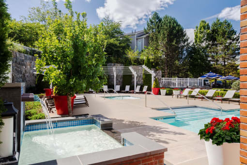 our apartments have a large pool and spa with chairs and plants at Residences at Stevens Pond, Massachusetts, 01906