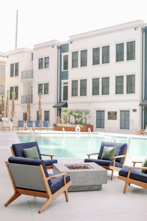 a swimming pool with chairs and a fire pit at The Merchant Apartments, South Carolina 29403