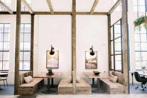 Indoor wooden pergola with wooden beams and two tables with benches on either side and oversized windows at The Merchant Apartments, Charleston, SC, 29403