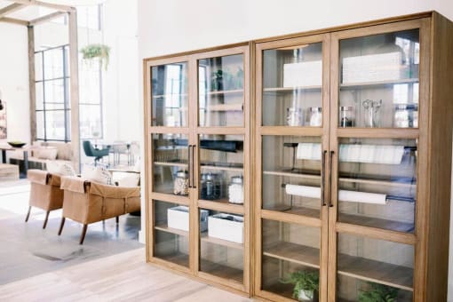 Resident lounge area with wooden and glass book cases with decorative items displayed at The Merchant Apartments, South Carolina 29403