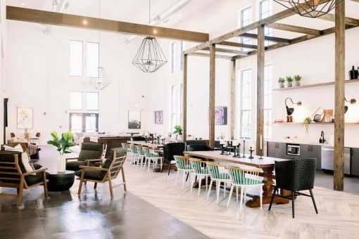 Spacious market-style resident lounge with tables and chairs for residents to relax and converse at The Merchant Apartments, Charleston, SC