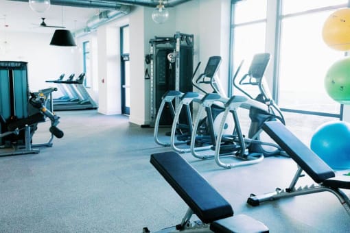 a gym with cardio equipment and large windows at The Merchant Apartments, Charleston