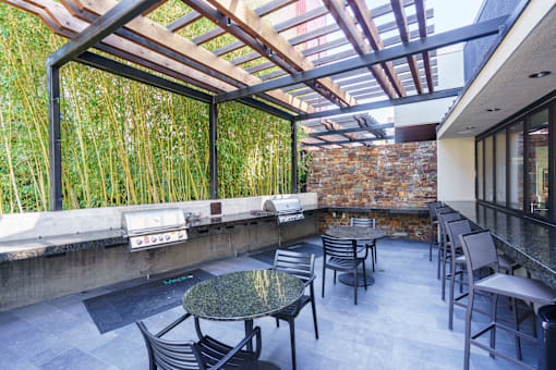 A patio with a table and chairs is surrounded by a bamboo wall.
