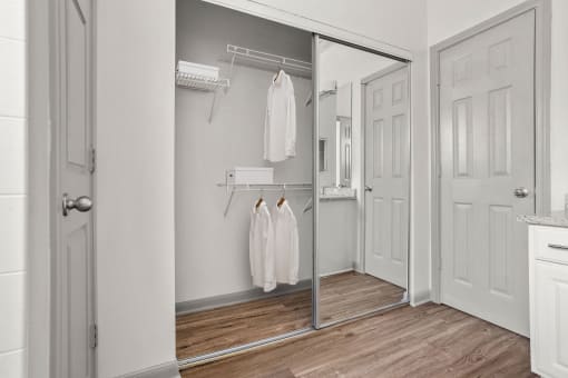 a walk in closet with white robes and a mirrored closet door at Aston at Cinco Ranch, Katy, 77450
