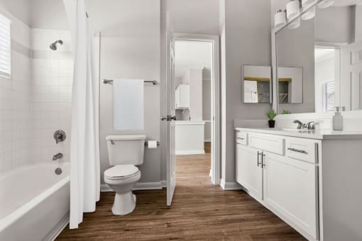 a white bathroom with a toilet and a tub at Aston at Cinco Ranch, Katy